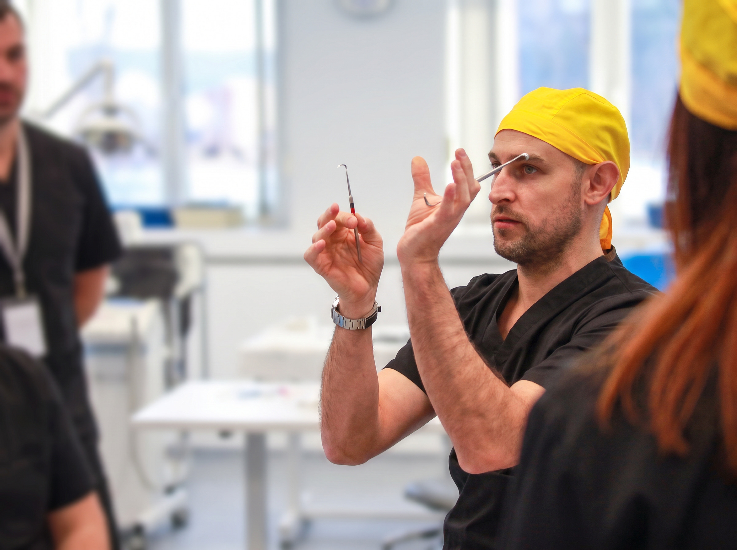 Clinician in yellow surgical cap demonstrating implant technique